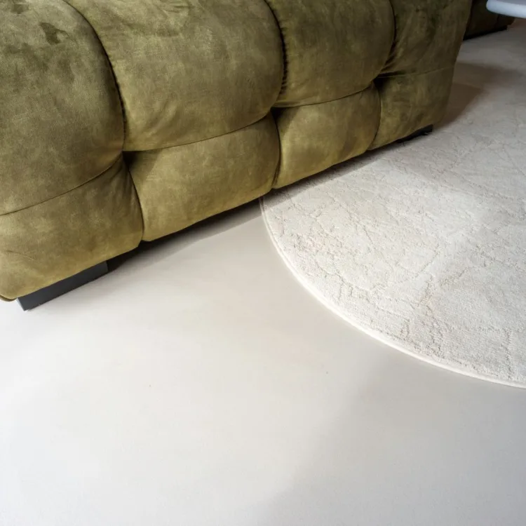 Corestone Nature Blend gietvloer in de kleur Summer beach met een groene bank en rond vloerkleed