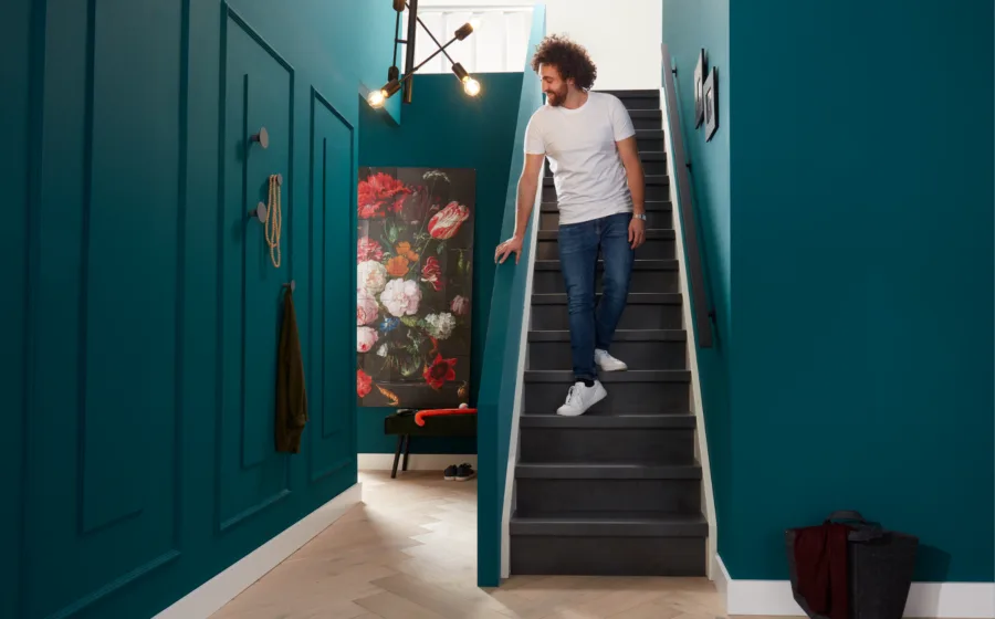 Man op donker grijze trap in de hal