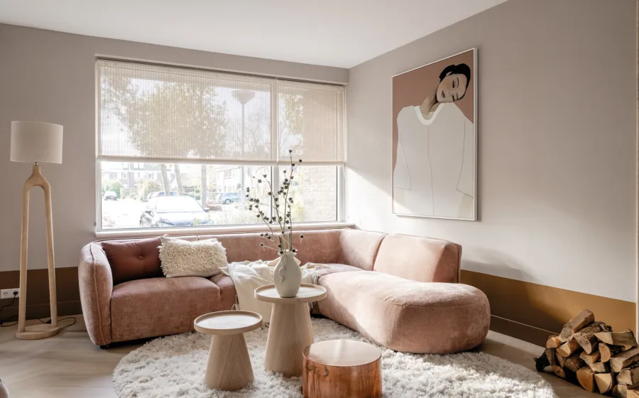 Knusse woonkamer met lichtdoorlatende raamdecoratie in pastelkleuren.