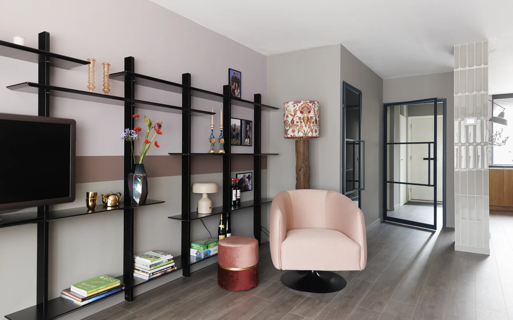 Moderne woonkamer met een bruine laminaatvloer en zwarte stalen deuren.