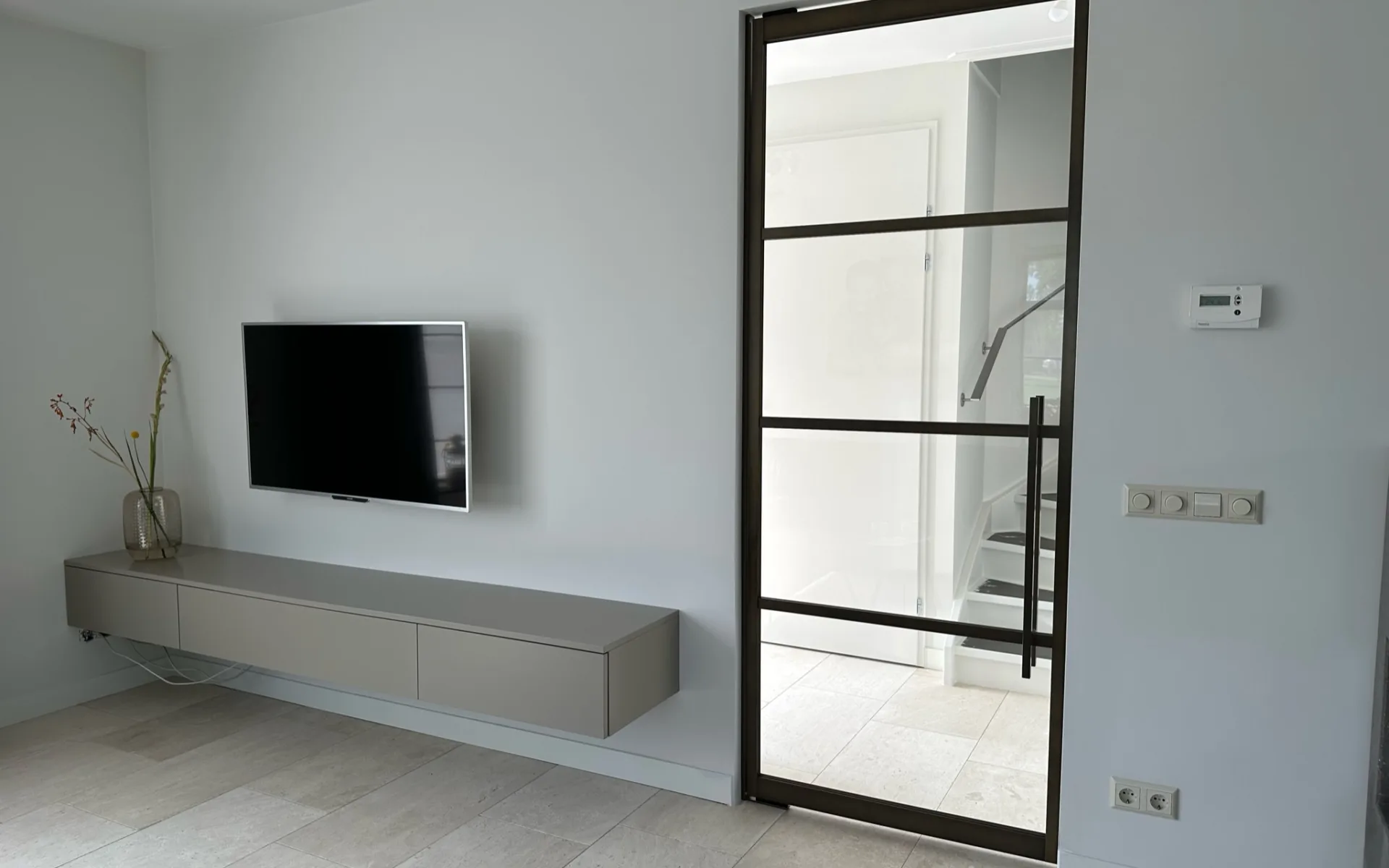 Woonkamer industriele stijl met lichte houten vloer, witte wanden en SolidDoor metalen deur met zwart frame.