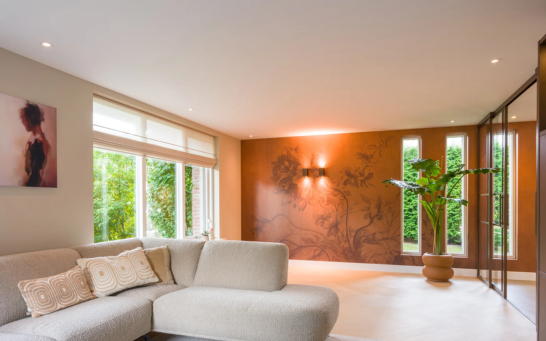 Woonkamer met visgraaat Lindura vloer, hoekbank, witte vouwgordijnen en roestrood behang van Kek