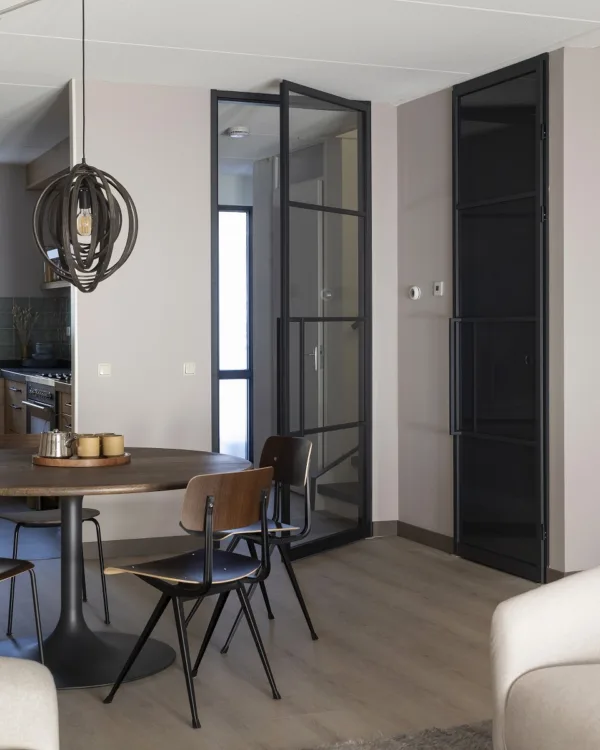 Strakke en moderne woonkamer met een grijsbruine laminaatvloer en een glazen stalen deur.