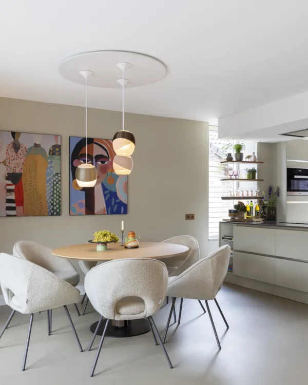 Keuken met ronde eetrafel, knusse stoelen, lichtgrijze gietvloer en prachtige sfeerverlichting.
