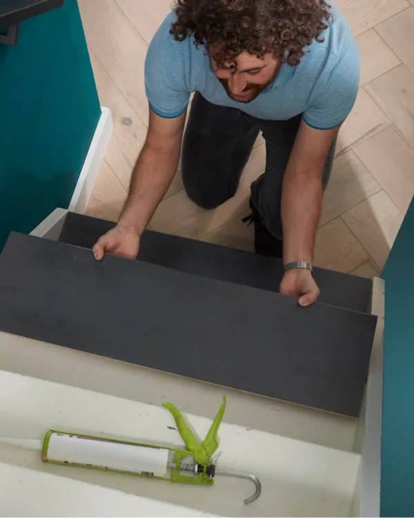 Vakman legt donker grijze overtrede op witte trap