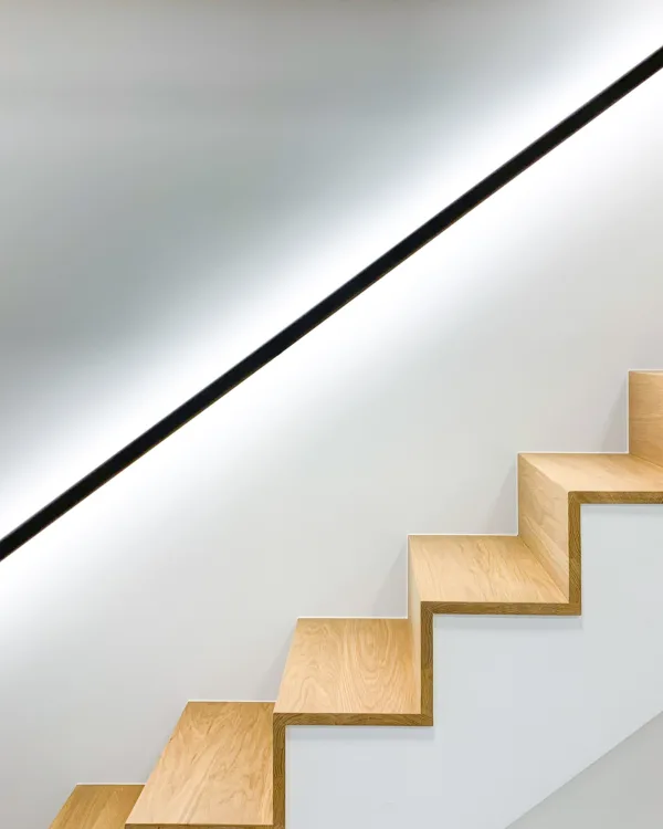 Detail trap met led trapleuning waarbij het licht zijwaarts op de muur schijnt