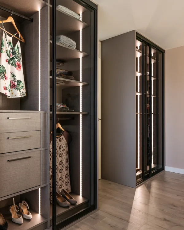 Slaapkamer met taupe kleurige schuifdeurkast op maat met glazen deuren en led-verlichting. Uit vtwonen in Vinkeveen, in samenwerking met Aanhuis.nl.