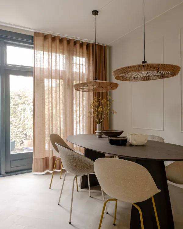 Sfeervolle eetkamer met transparante gordijnen in een warme beige tint.
