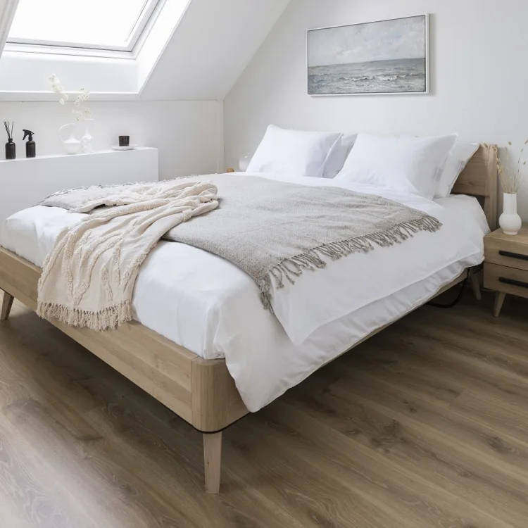 Ruime slaapkamer met een warmbruine laminaatvloer en veel natuurlijk licht.