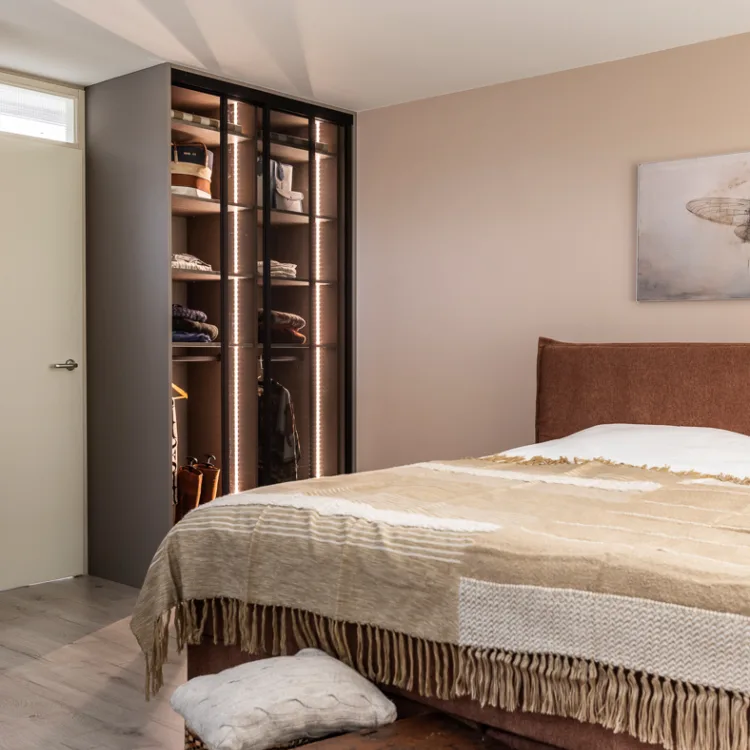 Slaapkamer met praktische kledingkast op maat met glazen deuren en led verlichting, zo liggen jouw kleren overzichtelijk klaar.