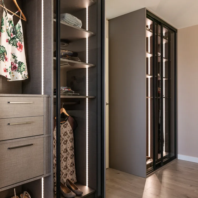 Slaapkamer met taupe kleurige schuifdeurkast op maat met glazen deuren en led-verlichting. Uit vtwonen in Vinkeveen, in samenwerking met Aanhuis.nl.