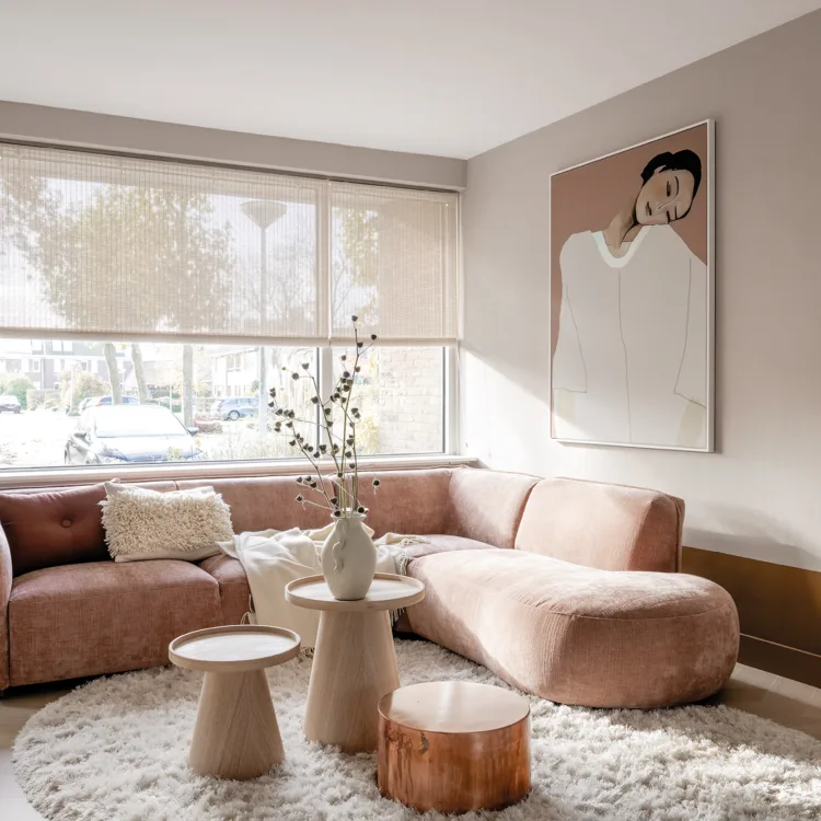 Knusse woonkamer met lichtdoorlatende raamdecoratie in pastelkleuren.